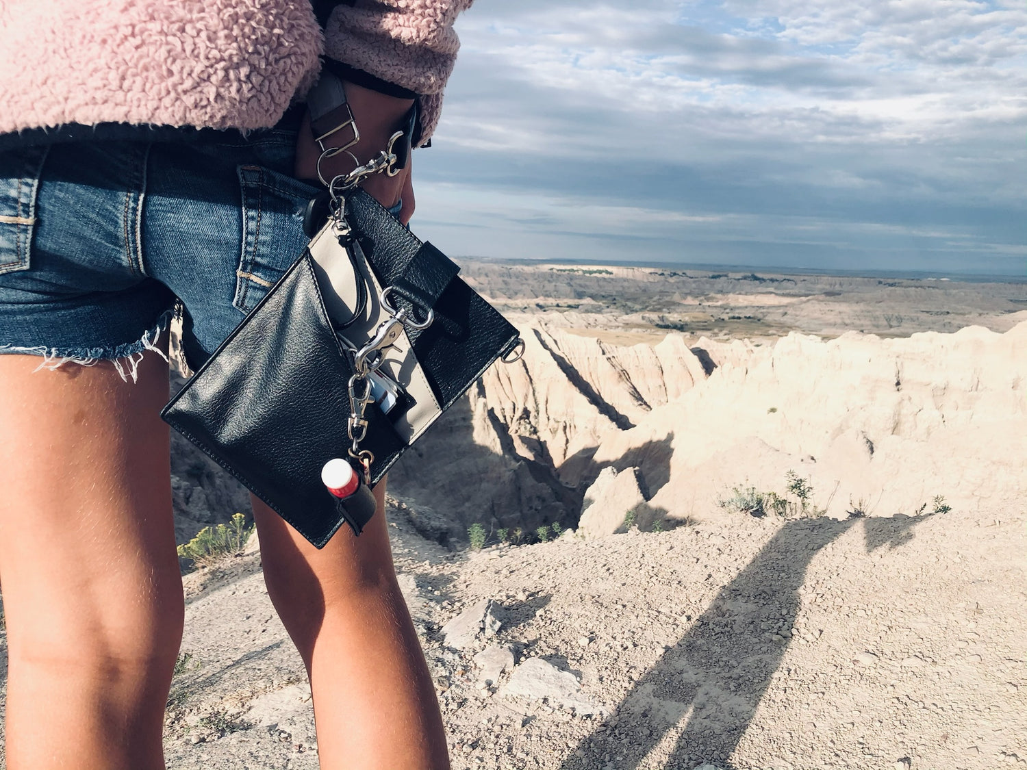 A human with a phone pouch looking out at a scenic view.